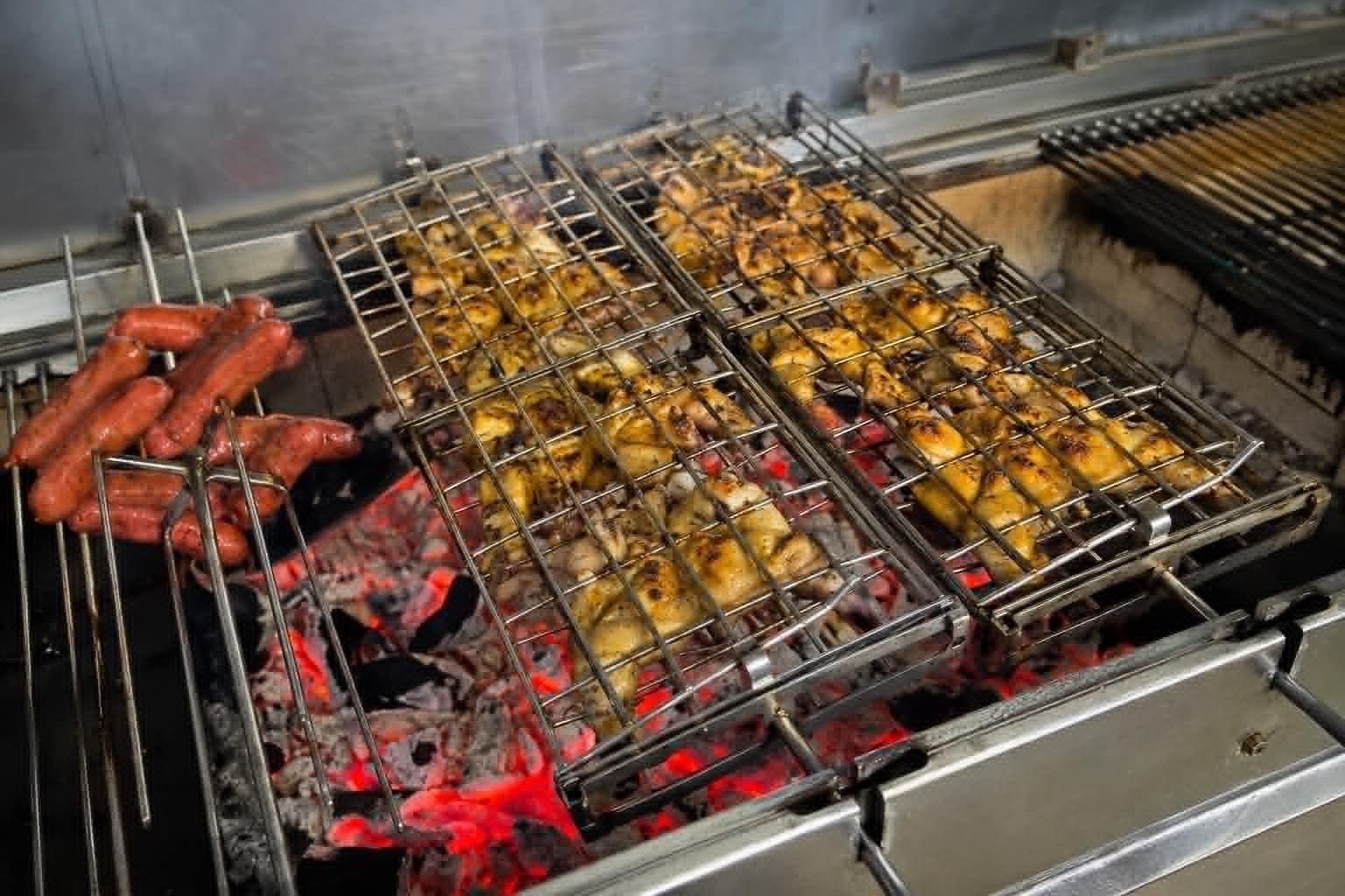 Frango e linguiça na grelha sobre brasas vivas na Sal & Brasa